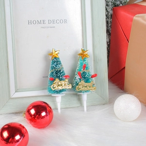 Mini green flocked Christmas tree cake toppers with gold stars on white fur background