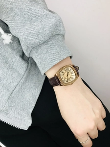Detail of rose gold rectangular watch with rhinestone bezel and brown leather strap