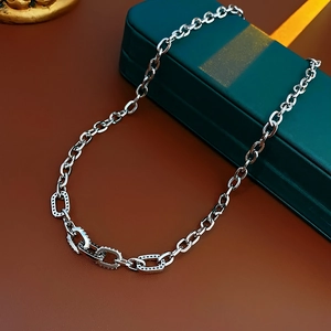 Detailed shot of a silver square linked necklace with zircon stones on a jewelry box