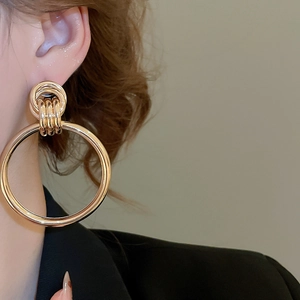 Detailansicht der übergroßen geometrischen goldenen Ohrringe getragen zu einem Blazer