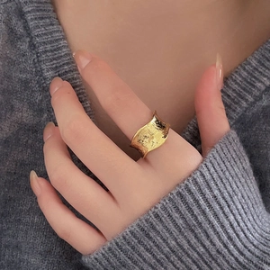 Golden irregular wavy wide band ring with metallic texture on a model's hand