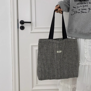 Detail of herringbone woven tote bag with black strap and ATYRG brand logo patch