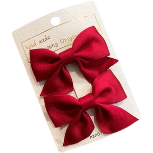Handmade red bow hair clips for girls set on a textured white display card