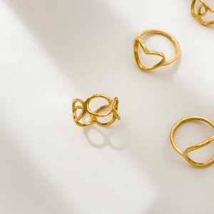 Three minimalist gold rings set featuring hollow heart and geometric wave designs on white background