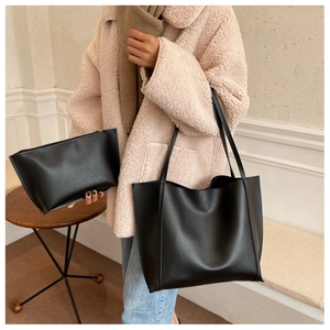 Detail of minimalist black faux leather tote bag set including matching zipper clutch