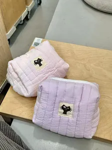 Detail view of pink and purple quilted cotton makeup bags with cute black cat patches