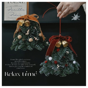 Detail of a handmade mini Christmas tree ornament with pine needles and a golden bell