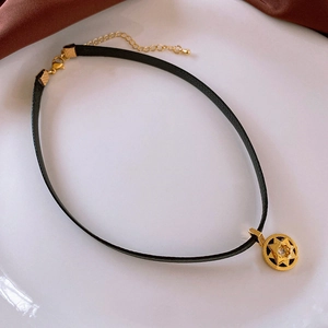 Macro shot of black leather choker with star pendant on white plate with brown silk