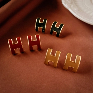 Vintage enamel H-letter stud earrings in black, red, and caramel on silk fabric