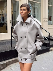 Detail of light grey double-breasted trench coat with broad lapels and belted waist