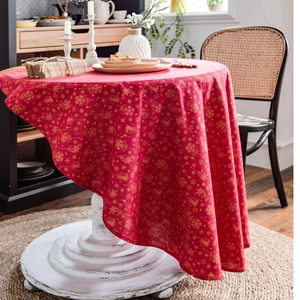 Christmas red tablecloth with gold snowflake patterns on round table in cozy room decor