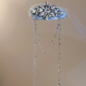 Detailed macro view of rhinestone flower design on a light blue velvet hair clip with fringe
