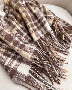 Detailed texture of a classic plaid tassel scarf in coffee and camel cashmere-like fabric