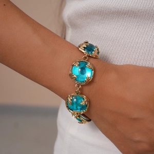 Détails d'un bracelet doré vintage orné de grandes pierres en résine bleue et motifs ciselés
