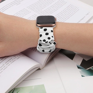 Close-up of white scrunchie watch band with black polka dots on a wrist with a magazine