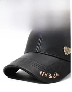 Detail of black leather baseball cap with gold NY&JA embroidery and vintage metal badge