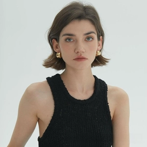 Close-up of model wearing chunky irregular gold C-shaped hoop earrings for a luxury look