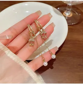 Detail of long gold tassel earrings with tulip design, diamonds and white pearls