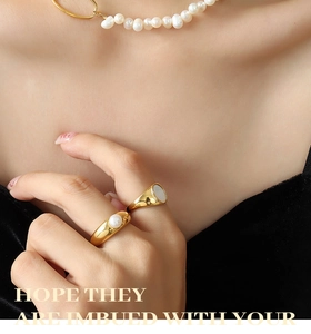 Detail of gold signet ring with mother of pearl and circular pearl ring on model