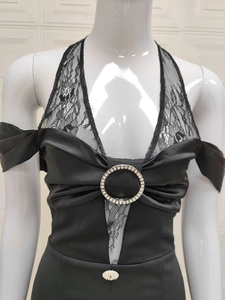 Détail de robe dos nu en dentelle noire avec anneau serti de strass brillants sur le buste