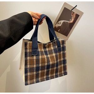 Detailed view of the brown and blue plaid canvas tote bag with sturdy handles