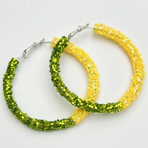 Macro detail of oversized green and yellow glitter hoop earrings for sports events