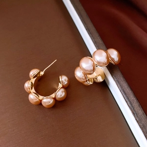 Vue macro de boucles d'oreilles créoles en C plaqué or 18K avec perles roses