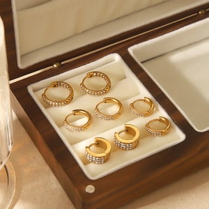Close-up of four pairs of 18k gold plated hoop earrings with zircons in a wooden box