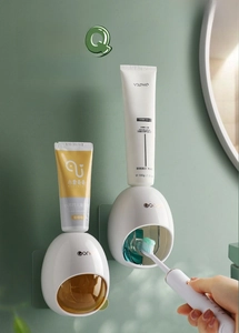 Detail of automatic toothpaste dispensers in white ABS mounted on a green bathroom wall