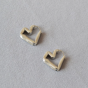 Minimalist silver geometric folded heart earrings with a polished mirror finish on fabric
