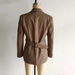 Detail of houndstooth blazer back featuring a brown fabric belt and vintage gold buckle