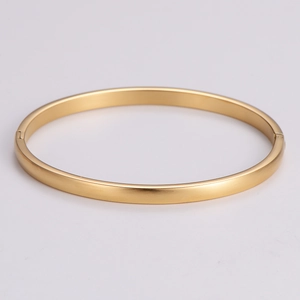 Detail of minimalist gold metal bracelet with matte brushed texture and side clasp closure