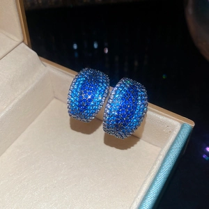 Macro shot of C-shaped earrings with blue gradient cubic zirconia in a jewelry box