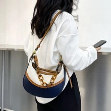 Detail of color-block crescent bag with navy white leather and amber resin chain