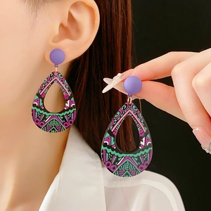 Gros plan de boucles d'oreilles bohèmes en forme de goutte aux motifs ethniques colorés