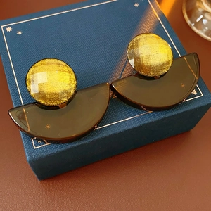 Macro view of geometric resin fan earrings with yellow glitter and brown translucent parts