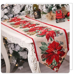 Close-up of knitted Christmas table runner with red poinsettia and pinecone patterns