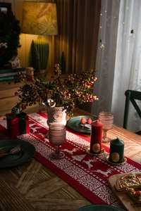 Close-up of red knitted Christmas table runner with white reindeer and snowflake patterns