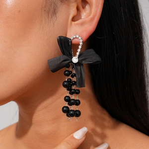 Detail view of large black silk bow earrings with beaded tassels and sparkling crystals