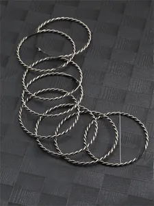 Detail of twisted silver metal bangles set showing intricate woven texture and 71.5mm diameter