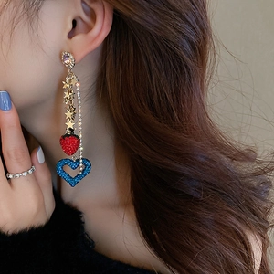 Detail of tassel earrings with red strawberry and blue heart charms on model