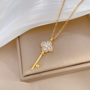 Macro shot of gold clover key pendant with pavé crystals in a luxury jewelry box