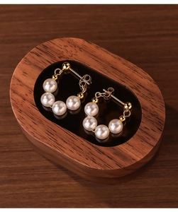 Detail of S925 silver beaded earrings with pearls on a luxury black mirror stand