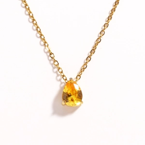 Detailed view of a gold chain necklace featuring a brilliant pear-cut yellow gemstone