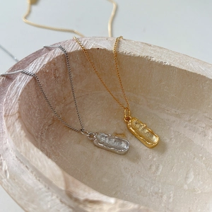 Detail of gold and silver irregular lava texture pendants on minimalist necklaces