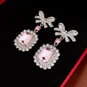 Detail of silver bow earrings with pink rectangular crystal drop in a velvet box