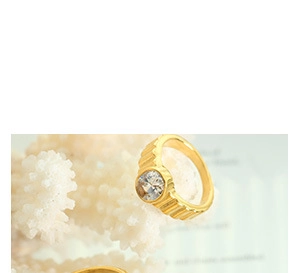 Detail of a gold-plated ribbed ring featuring a central sparkling round crystal stone