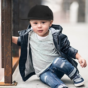 Close-up of kids black flat brim hip hop hat paired with leather jacket and denim jeans