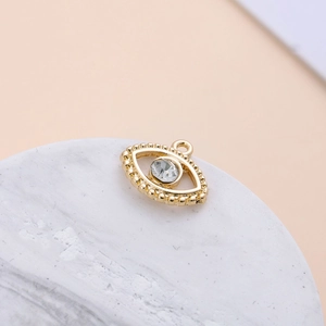 Close-up of gold-plated eye pendant with crystal inlay on marble display stand