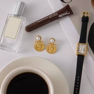 Close-up of vintage gold titanium steel coin earrings with queen portrait relief